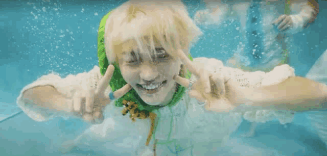 a person is swimming in a pool and making a peace sign