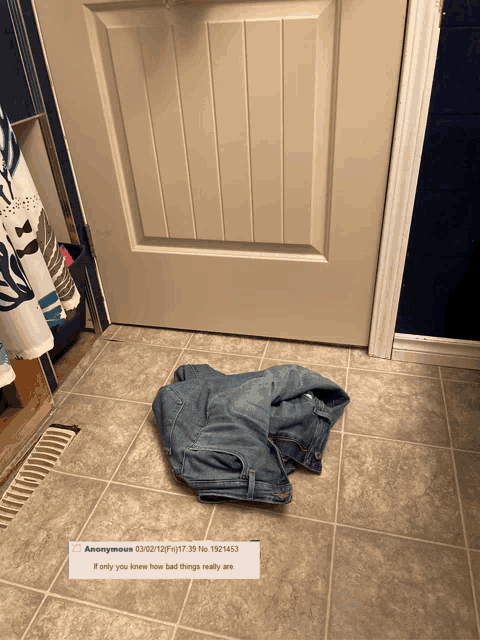 a pair of jeans laying on a tiled floor next to a door