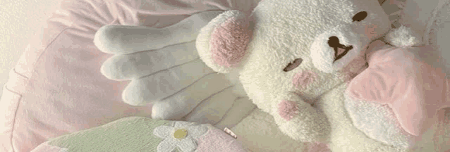 a teddy bear is laying on top of a pink pillow .