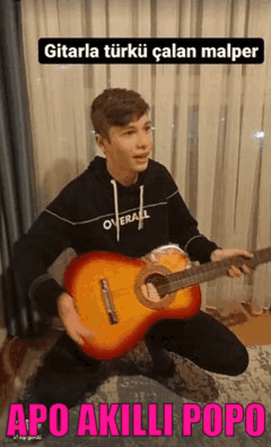 a young man is kneeling down while holding a red guitar .