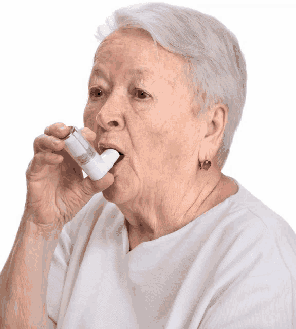 an elderly woman in a white shirt is using an inhaler in her mouth