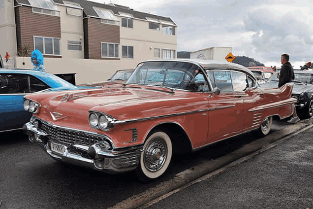 a red cadillac is parked on the side of the road with a license plate that says vmnyc