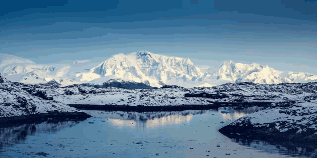 a snowy mountain is reflected in a lake