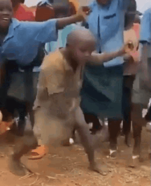 a group of children are dancing in a dirt field . one of the children is wearing a blue shirt .