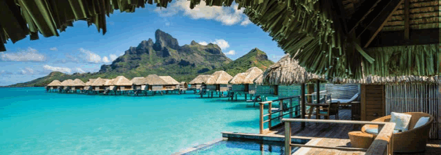 a row of thatched huts sit on stilts in the ocean