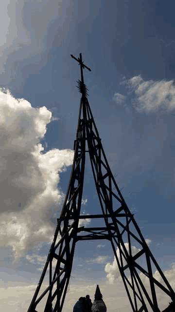 a large metal tower with a cross on top of it