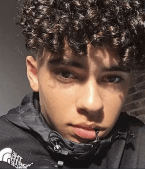 a young man with curly hair is wearing a black jacket with the north face on it