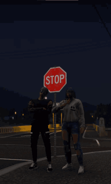 two people standing in front of a stop sign at night