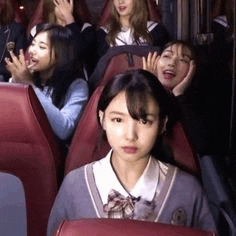 a group of girls are sitting in red chairs on a bus .