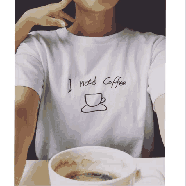 a person wearing a white shirt that says " i need coffee "