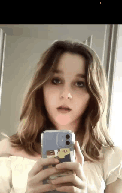 a girl taking a picture of herself with a phone