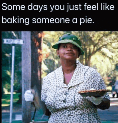 a woman in a green hat is holding a pie in her hand .