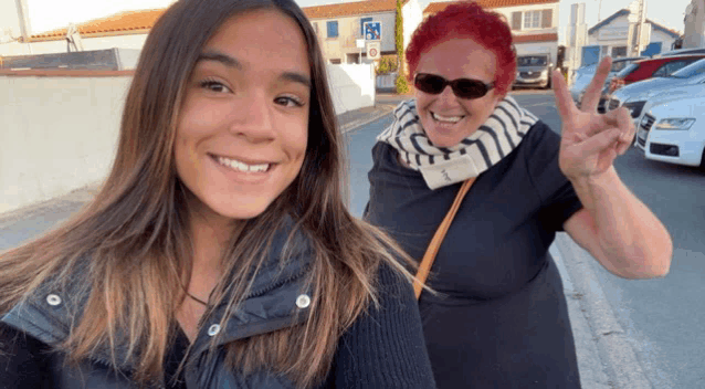 a woman with red hair giving a peace sign next to another woman