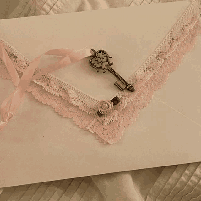 a white envelope with pink lace and a key on top