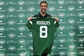 a man is holding a green jersey that says rodgers 8 .