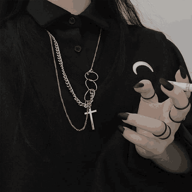 a woman wearing a black shirt with a crescent moon on it is holding a cigarette