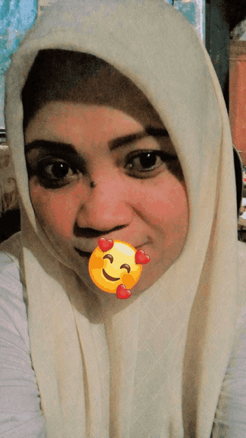 a woman wearing a white hijab has a yellow smiley face on her mouth