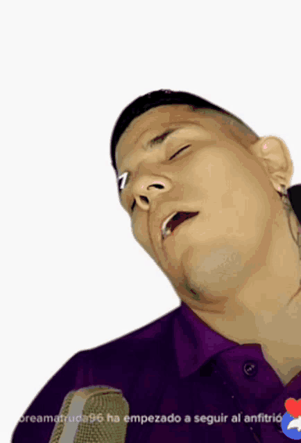 a man in a purple shirt is sleeping with his eyes closed in front of a microphone