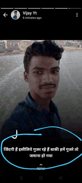 a young man with a mustache is taking a selfie in front of a body of water with a caption in hindi .