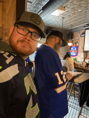 a man wearing a seahawks jersey stands next to a man wearing a bills jersey