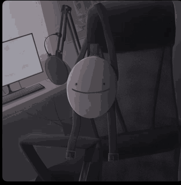 a smiley face is hanging from a chair in front of a computer