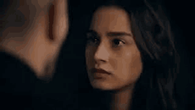 a man and a woman are looking at each other in a dark room in a close up of their faces .