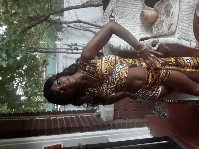 a woman in a dress with a greek key pattern is standing on a porch