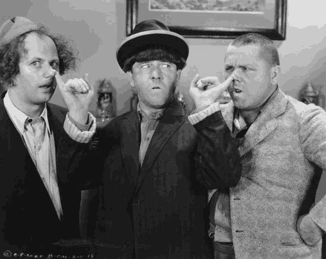 three men are standing next to each other and one of them is holding his nose in a black and white photo