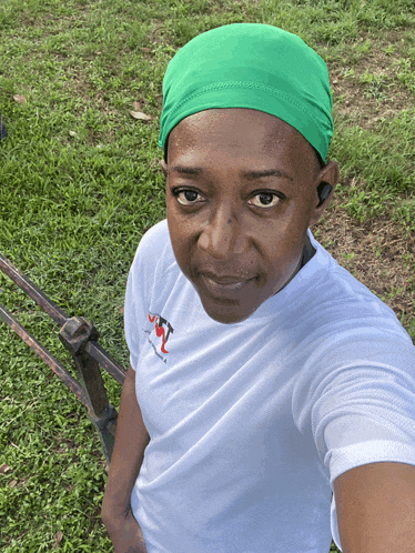 a woman wearing a white shirt and a green headband takes a selfie in the grass