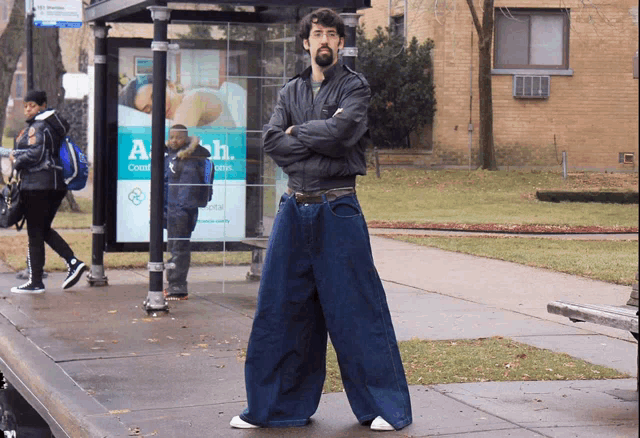 a man standing in front of a bus stop with a sign that says ' a ' on it