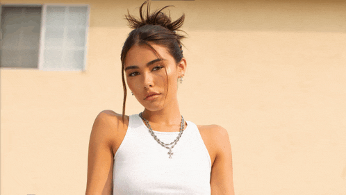 a woman wearing a white tank top and a necklace with a cross