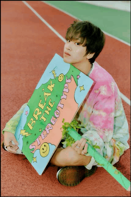 a young man holding a sign that says break the stereotype