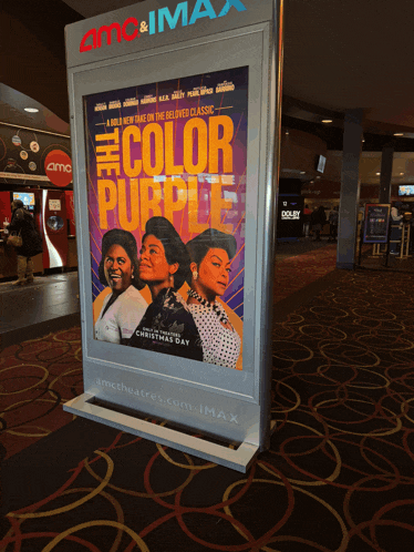 a movie poster for the color purple sits in a movie theater