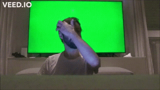 a man is sitting in front of a green screen that says veed.io on it