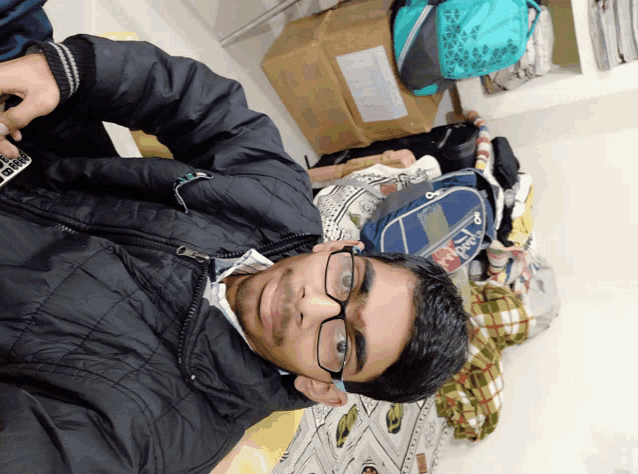 a man wearing glasses is laying on a bed in front of a box that says ' apollo ' on it