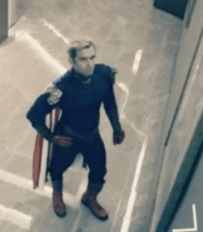 a man in a superhero costume is standing in a hallway holding a shield .