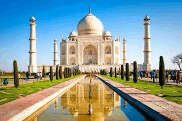 the taj mahal is a very large building with a lot of columns and a pond in front of it .