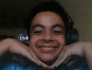 a young boy wearing headphones makes a heart shape with his hands