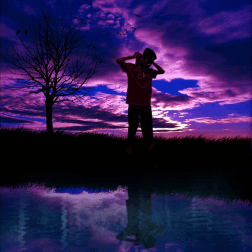 a man in a calvin klein shirt stands in front of a sunset