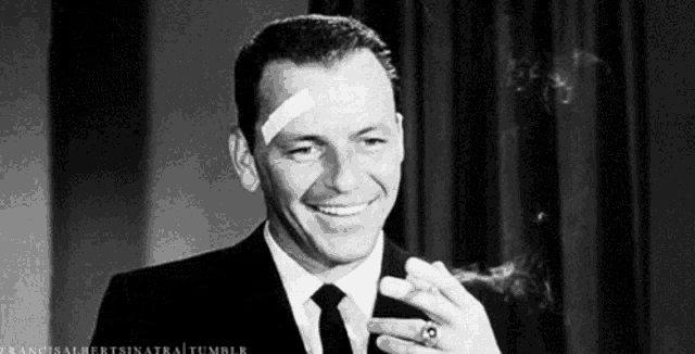 a man with a bandage on his head is smoking a cigar and smiling .