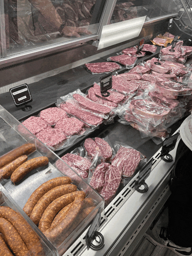 a variety of meats and sausages in a butcher 's display case