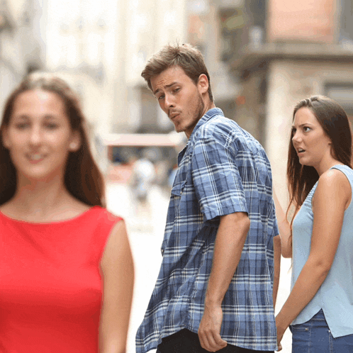 a man in a plaid shirt is walking down a street with two women