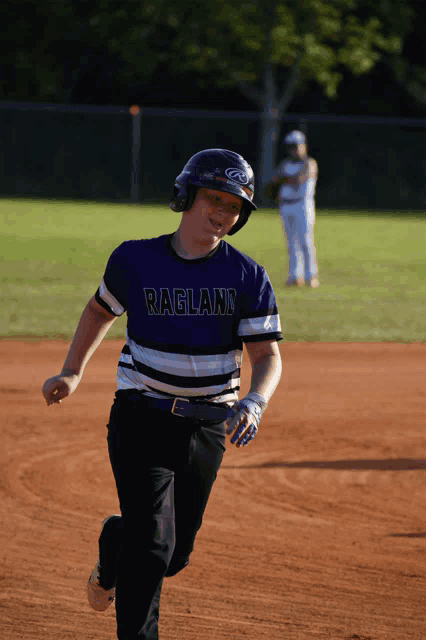 a baseball player wearing a ragland jersey is running towards home plate