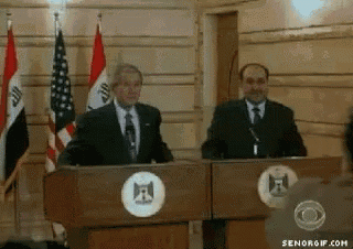 two men are standing at podiums with flags behind them and one of them has the letter f on his chest