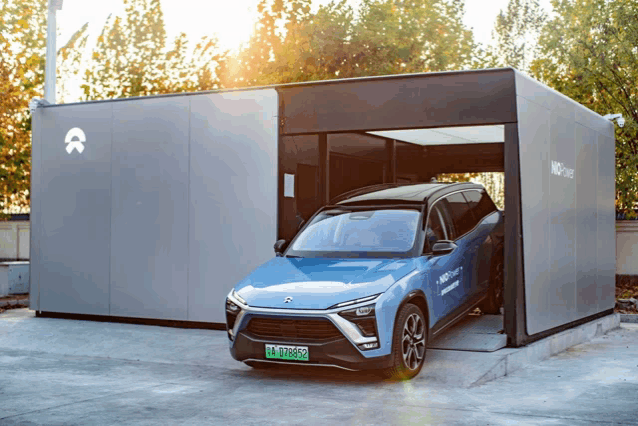 a blue car with a green license plate is parked in front of a building that says nmo charge