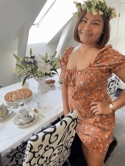 a woman with a flower crown on her head stands in front of a table