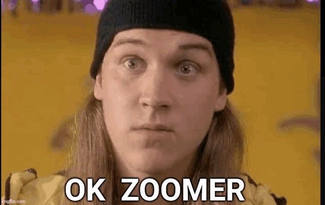 a man wearing a beanie and a yellow jacket is making a funny face and says `` ok zoomer '' .