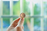 Close-up of hand holding up a gold coin