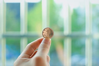 Close-up of hand holding up a gold coin