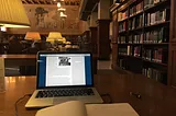 Laptop and notebook on a table in a library reading room